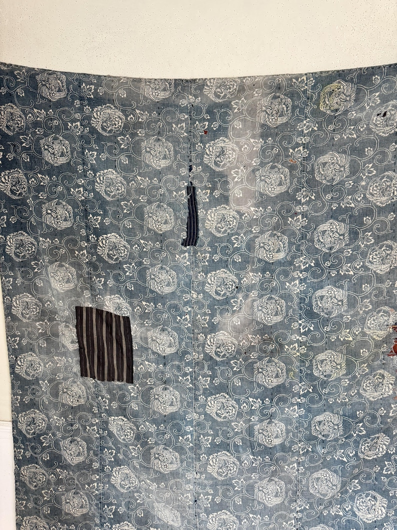 May include: A blue fabric with a white floral pattern. The fabric has been patched with different fabrics in a few places.
