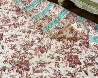 May include: A vintage quilt with a floral pattern in shades of brown and red on a white background. The quilt is made of two different fabrics, one with a striped pattern and the other with a floral pattern.