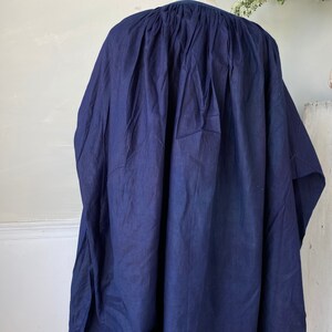 May include: A navy blue cotton tunic with a gathered neckline and a loose, flowing silhouette.
