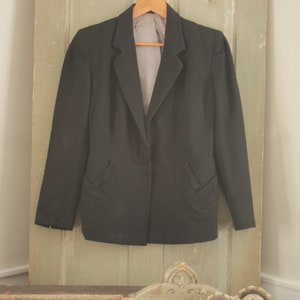 May include: A black blazer with a single button closure and decorative stitching on the pockets.
