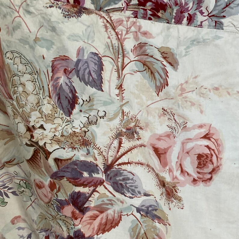 Puede incluir: Una tela blanca con un patr&oacute;n floral que presenta rosas rosas, hojas moradas y flores blancas. La tela tiene una est&eacute;tica vintage.