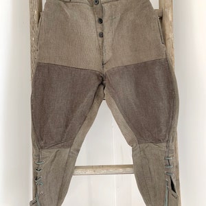 May include: A pair of brown corduroy riding breeches with a button fly and lace-up closures at the bottom of the legs.
