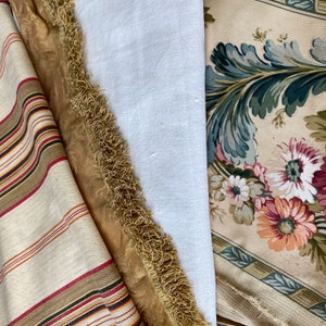 Puede incluir: Primer plano de tres muestras de tela. La primera es una tela a rayas con rayas marrones, rojas y blancas. La segunda es una tela dorada con un borde de flecos. La tercera es una tela blanca con un estampado floral en tonos verdes, rosas y marrones.