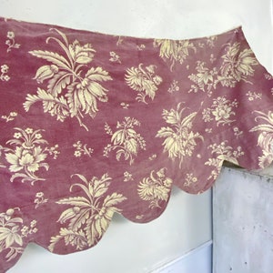 Può includere: Un tessuto con bordo a festoni, sfondo bordeaux e un motivo floreale color crema.