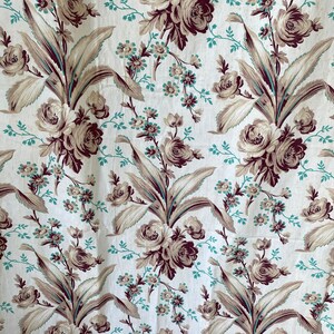 Könnte beinhalten: Ein weißer Stoff mit einem sich wiederholenden Muster aus braunen und beigefarbenen Blumen und Blättern. Die Blumen sind stilisiert und haben einen Vintage-Look.