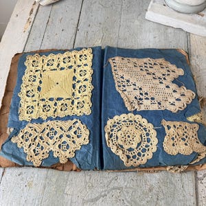 May include: A collection of vintage crocheted doilies in various shapes and sizes, displayed on a blue fabric background. The doilies are a pale yellow color and have intricate patterns.