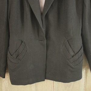 May include: A black blazer with a single button closure and unique, decorative stitching on the pockets.