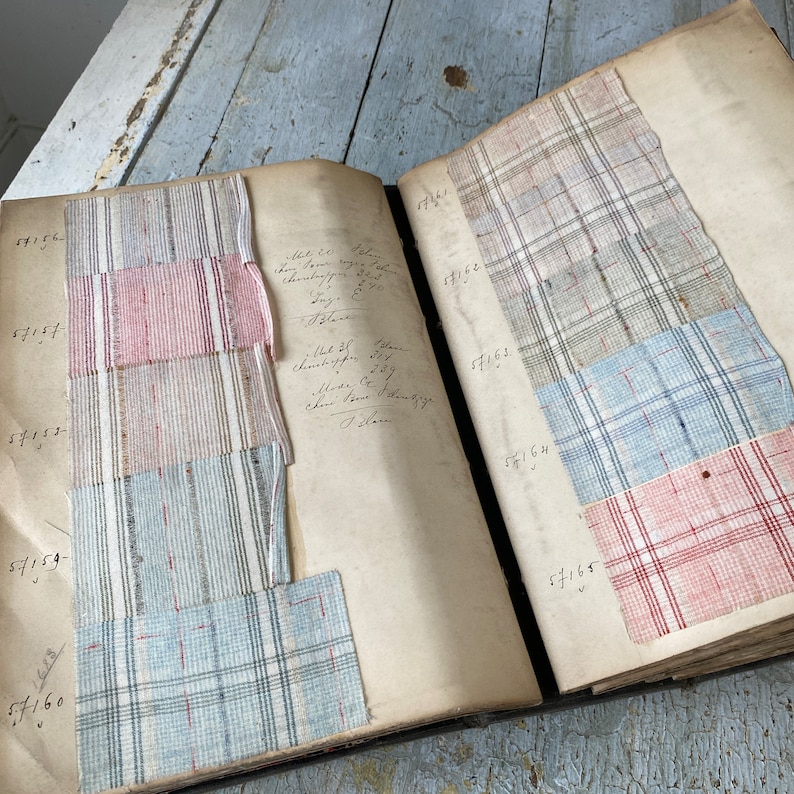 May include: A vintage fabric swatch book with numbered pages and various fabric samples. The samples include a red and white plaid, a blue and white plaid, and a light blue and white plaid.