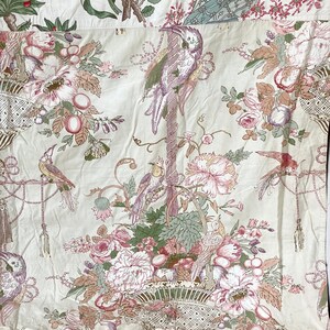 Puede incluir: Una tela blanca con un patr&oacute;n floral que presenta flores rosas y verdes, p&aacute;jaros y una cesta. La tela tiene una est&eacute;tica vintage.