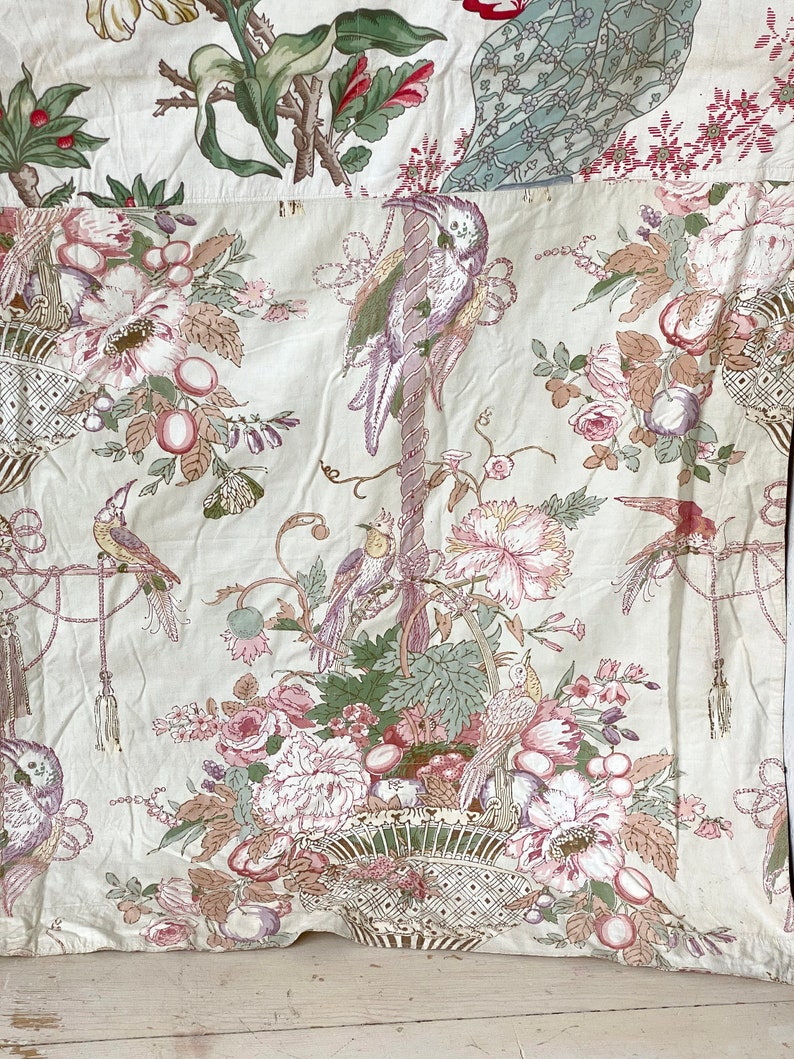 Puede incluir: Una tela blanca con un patr&oacute;n floral que presenta flores rosas y verdes, p&aacute;jaros y una cesta. La tela tiene una est&eacute;tica vintage.
