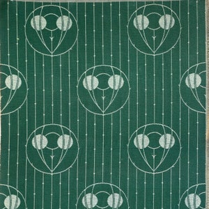 May include: A green fabric with a repeating pattern of white circles and lines. The circles are arranged in a circular pattern with three circles in each circle. The lines are arranged in a vertical pattern.
