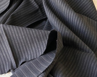 May include: Black and white striped fabric with a subtle sheen. The fabric is folded and draped, showing the texture and pattern.