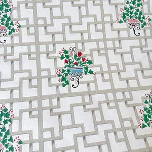 Op de afbeelding: Witte stof met een grijs traliewerkpatroon. Het ontwerp bevat potplanten met groene bladeren en rode bloemen. De potten zijn blauw, roze en wit en voegen kleuraccenten toe aan het herhalende patroon.
