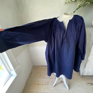 May include: A navy blue, long-sleeved tunic top with a gathered neckline and a relaxed fit.