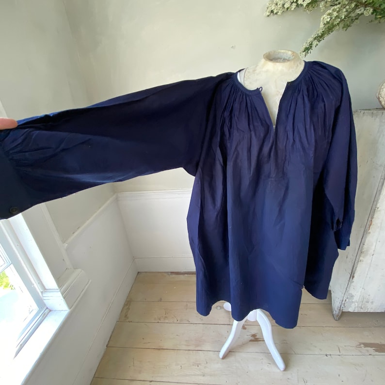 May include: A navy blue, long-sleeved tunic top with a gathered neckline and a relaxed fit.