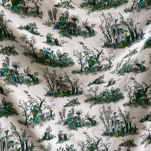 Op de afbeelding: Een witte stof met een herhalend patroon van groene bomen, struiken en figuren in een pastorale setting. De figuren zijn gekleed in 18e-eeuwse kleding en zijn bezig met verschillende activiteiten, zoals het onderhouden van tuinen, het maken van muziek en het omgaan met dieren.