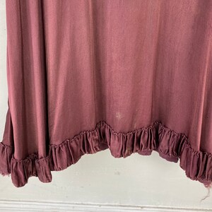 May include: A burgundy skirt with a ruffled hem. The skirt is made from a soft, flowing fabric.