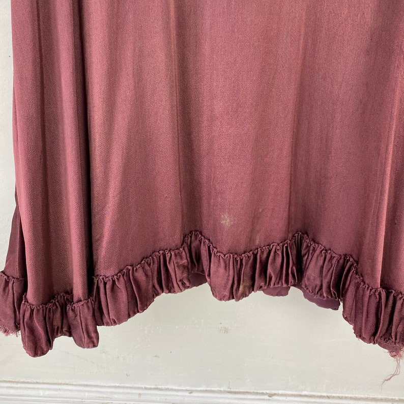 May include: A burgundy skirt with a ruffled hem. The skirt is made from a soft, flowing fabric.
