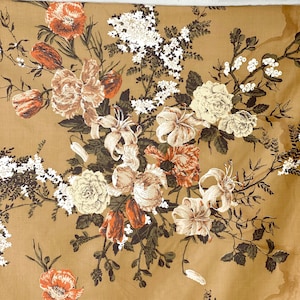 May include: A beige fabric with a floral pattern featuring white, pink, and brown flowers. The flowers are arranged in a repeating pattern and are surrounded by green leaves.