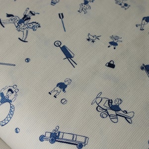 Pode incluir: Um tecido branco com um padrão azul de crianças brincando. O padrão inclui crianças brincando com um tambor, um avião de brinquedo, um cavalo de balanço, um caminhão de brinquedo e outros brinquedos.