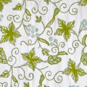 May include: White fabric with an embroidered design of green leaves and vines. The design is reminiscent of a grapevine.