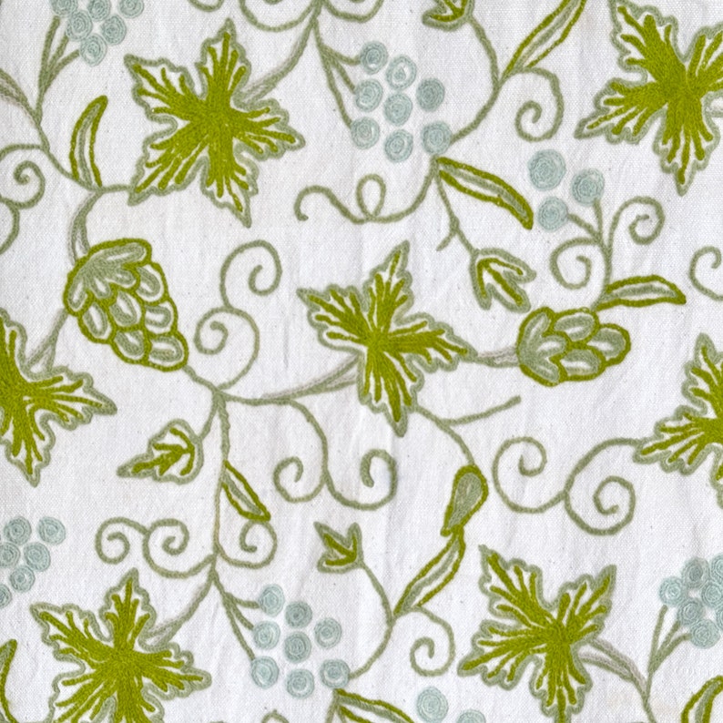 May include: White fabric with an embroidered design of green leaves and vines. The design is reminiscent of a grapevine.