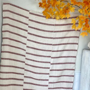 May include: A white and red striped throw blanket with a woven texture. The blanket is made of natural fibers and has a rustic look.