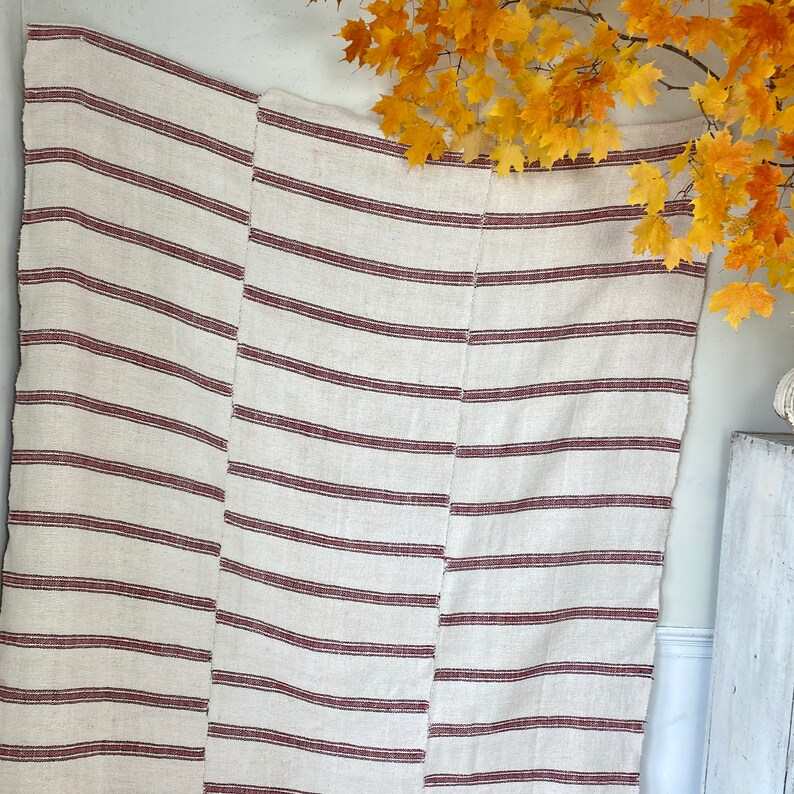 May include: A white and red striped throw blanket with a woven texture. The blanket is made of natural fibers and has a rustic look.