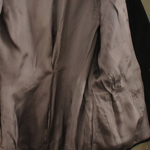May include: A black blazer with a gray satin lining. The blazer has a double-breasted closure and a single button on the right side.