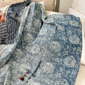 May include: A blue and white vintage Japanese cotton quilt with a floral pattern. The quilt is made of several pieces of fabric sewn together, and has a distressed look.