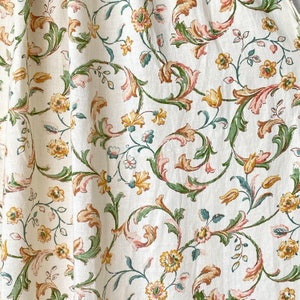 Könnte beinhalten: Cremefarbener Stoff mit einem sich wiederholenden Blumenmuster. Das Design zeigt gelbe, rosa und grüne Blumen und Blätter. Der Stoff hat eine klassische, Vintage-Ästhetik, geeignet für Vorhänge oder Polster.