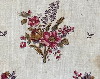 May include: A white fabric with a repeating pattern of pink and brown flowers with green leaves. The flowers are in clusters and have a vintage look.