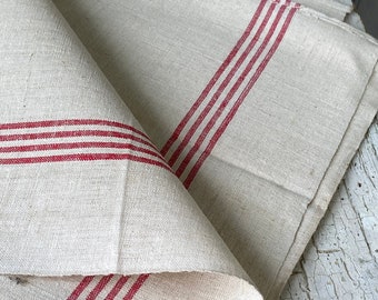 May include: Two white linen tea towels with red stripes. The towels are folded and layered on top of each other.