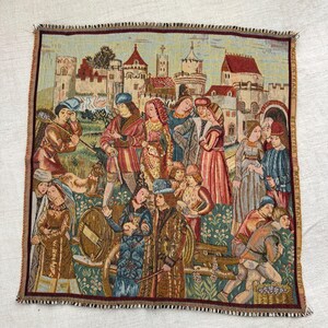 May include: Tapestry featuring a medieval scene with figures in period clothing, a castle backdrop, and a border with a frayed edge. The tapestry is made in France.