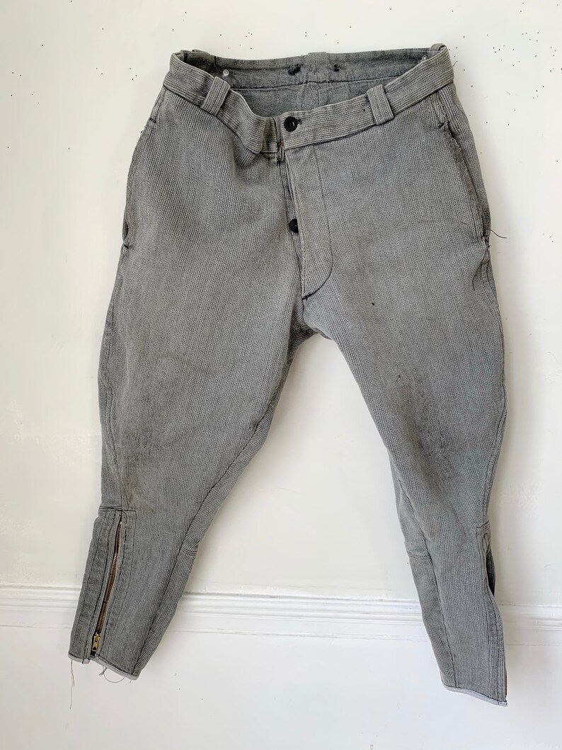 May include: A pair of gray riding breeches with a zipper at the bottom of each leg.