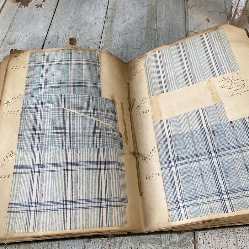 May include: An antique fabric sample book with pages of different blue and white plaid patterns. The pages are labeled with numbers and some have handwritten notes.