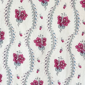 Könnte beinhalten: Ein weißer Stoff mit einem sich wiederholenden Muster aus rosa Blüten und blauen Ranken. Die Blüten haben ein fünfblättriges Design und sind von kleinen blauen Blättern umgeben.