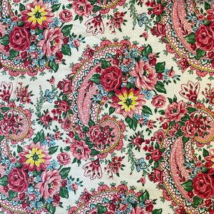 May include: Floral fabric with a paisley design. The fabric features a repeating pattern of pink and red roses, yellow and blue flowers, and green leaves on a white background. The paisley elements are outlined in pink and red.