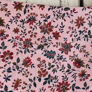 May include: Pink fabric with a repeating floral pattern. The flowers are in shades of red, brown, and green. The fabric has a linen texture.