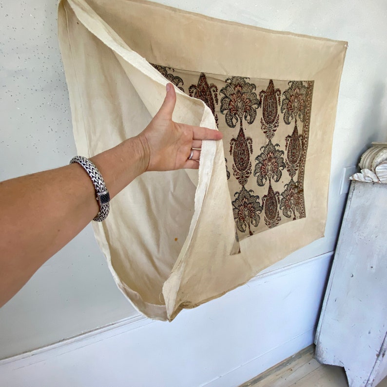 Pu&ograve; includere: Un arazzo da parete in tessuto color crema con un motivo paisley in tonalit&agrave; di rosso, nero e verde. Il tessuto &egrave; ripiegato per rivelare il retro semplice color crema.