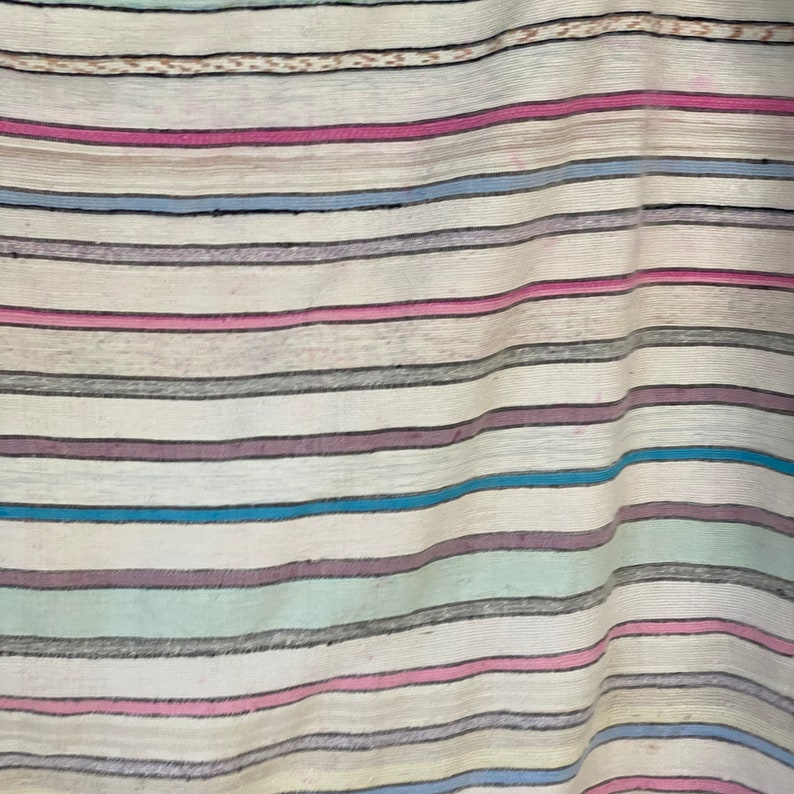May include: A white fabric with horizontal stripes in various colors, including pink, blue, gray, and green.