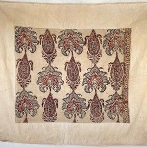 Pu&ograve; includere: Un tessuto tessile bianco con un motivo ripetitivo di motivi paisley in tonalit&agrave; di rosso, blu e nero. Il tessuto ha una texture sottile e un aspetto leggermente usurato.