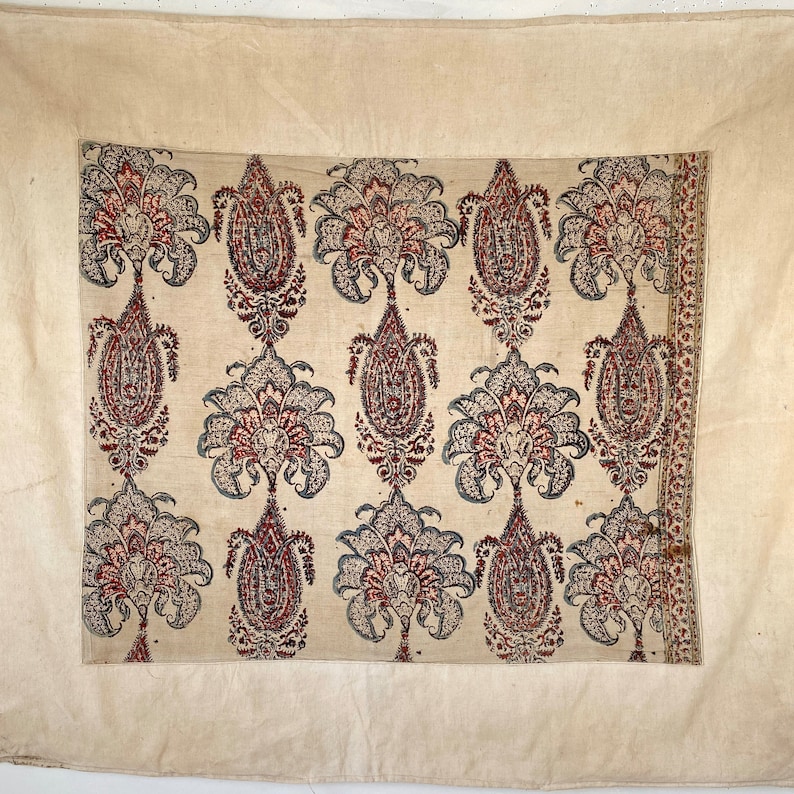 Pu&ograve; includere: Un tessuto tessile bianco con un motivo ripetitivo di motivi paisley in tonalit&agrave; di rosso, blu e nero. Il tessuto ha una texture sottile e un aspetto leggermente usurato.