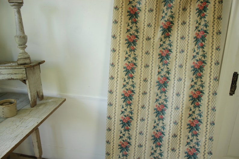 K&ouml;nnte beinhalten: Ein Vintage-Blumenstoff mit einem sich wiederholenden Muster aus rosa Bl&uuml;ten und gr&uuml;nen Bl&auml;ttern auf cremefarbenem Hintergrund. Der Stoff hat ein dezentes Karomuster.