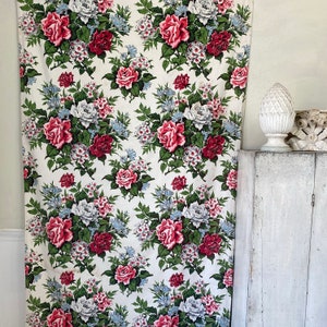 Könnte beinhalten: Ein weißer Stoff mit einem sich wiederholenden Muster aus rosa und roten Rosen, grünen Blättern und weißen Blüten. Der Stoff hat einen Vintage-Look und wäre perfekt für eine Vielzahl von Bastelprojekten.