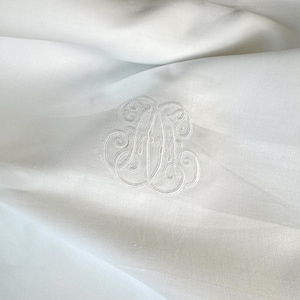 May include: White linen tablecloth with a large embroidered monogram in the centre.