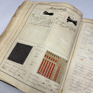 May include: A close-up of a page from a vintage fabric sample book. The page features a black and white striped fabric sample, a red and white woven fabric sample, and handwritten notes about the fabric's properties, including the thread count, width, and length.