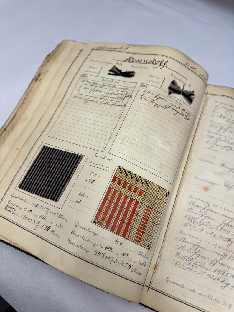 May include: A close-up of a page from a vintage fabric sample book. The page features a black and white striped fabric sample, a red and white woven fabric sample, and handwritten notes about the fabric's properties, including the thread count, width, and length.