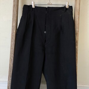 May include: Black pleated pants with a button fly and a single button closure at the waist.