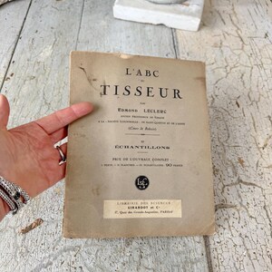 Pode incluir: Um livro vintage intitulado "L'ABC TISSEUR" de Edmond Leclerc, antigo professor de tecelagem. O livro &eacute; publicado por Librairie des Sciences Girardot et C, 27 Quai des Grands Augustins, Paris.